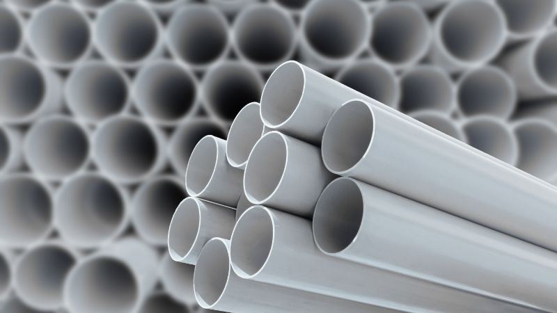 Bungkos ng puting PVC pipe na pinutol sa tamang haba sa dulo ng extrusion line