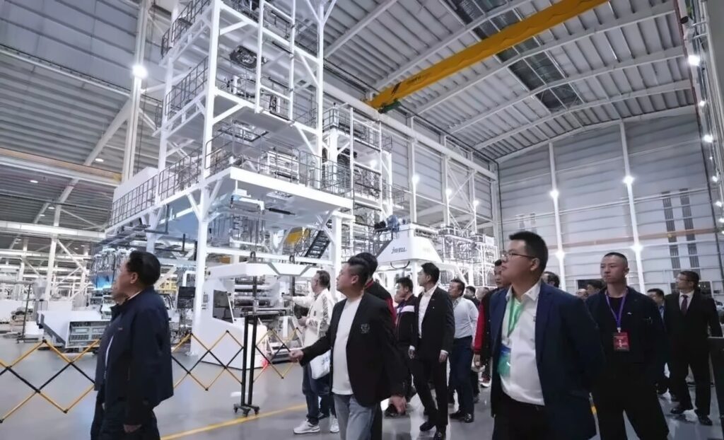 Visitors beside large extrusion equipment on the JWELL workshop floor