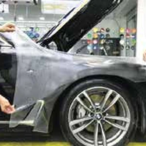 Pose d’un film transparent de protection de peinture sur une voiture noire