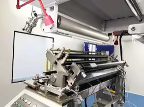 Close-up of precision rollers on a coating machine with overhead task lights