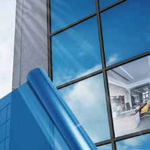 Rouleau de film pour vitres bleu devant une façade de bâtiment en verre
